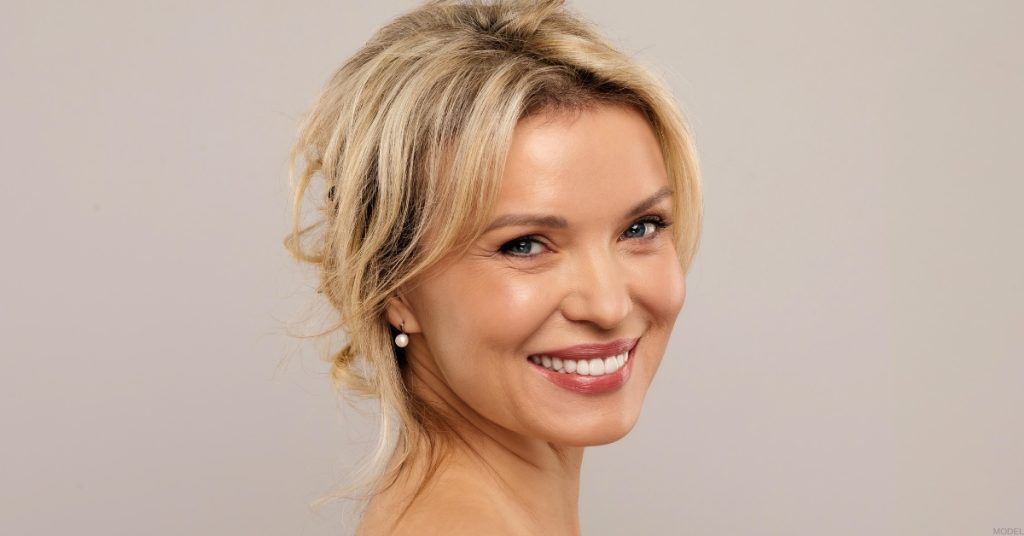 woman with blonde hair smiling over her shoulder (model)